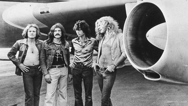 Led Zeppelin members posing in front of a plane. Photo by Julio Zeppelin
