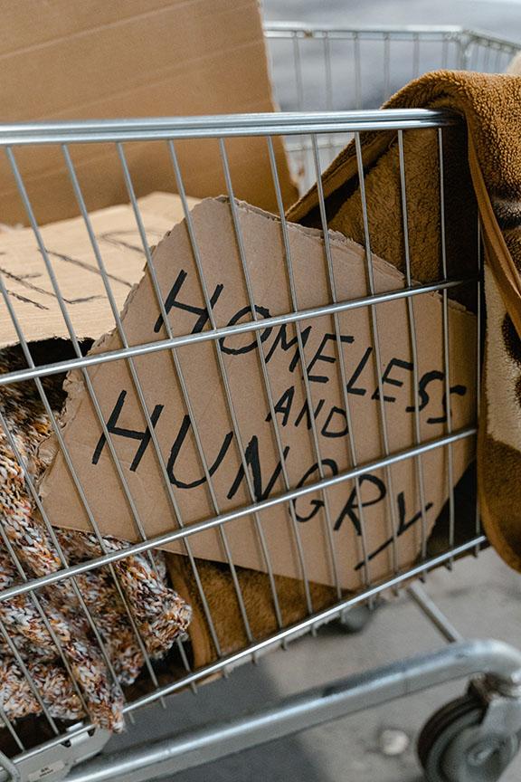 A shopping cart with a â€œHomeless and Hungryâ€ sign written by a homeless person in SLO. Photo by Mart Production