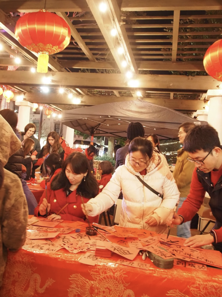 Tom Wei (right) and Phoenix Fang (white jacket, center) invite people of all ages to paint symbols and characters of luck, prosperity and other blessings onto paper at the downtown SLO Lunar New Year celebration on Feb. 19.