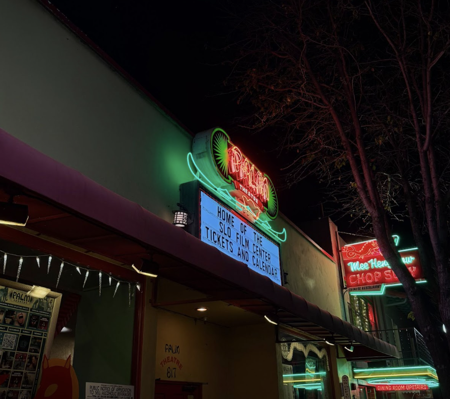 The neon lights of the Palm Theatre entrance sign lighting up the sidewalk. It catches people’s attention from all around.
